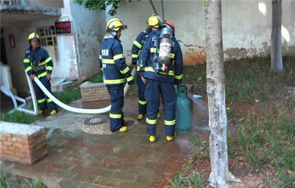 Spontaneous combustion of gas canisters in the Kunming residents and firemen hold a burning gas canisters rushed out of homes
